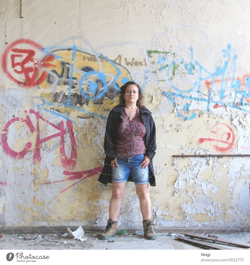 Portrait of a woman with short jeans, colourful blouse and dark jacket standing in front of a ramshackle wall with graffiti Human being Feminine Woman Adults 1