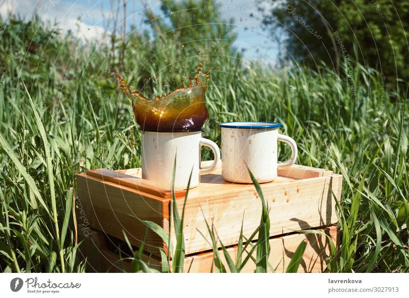 enamel mugs on a wooden box with splashing beverage Spring Grass Tea Exterior shot Beverage Drinking Wood Splashing Hot Cup Enamel Coffee Picnic Hiking Summer