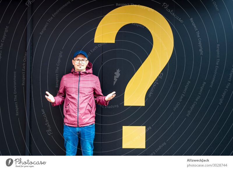 Young man with a rain jacket next to a yellow question mark Question mark Ask Decide Unclear Marvel Think Meditative Recklessness 1 Person Central perspective