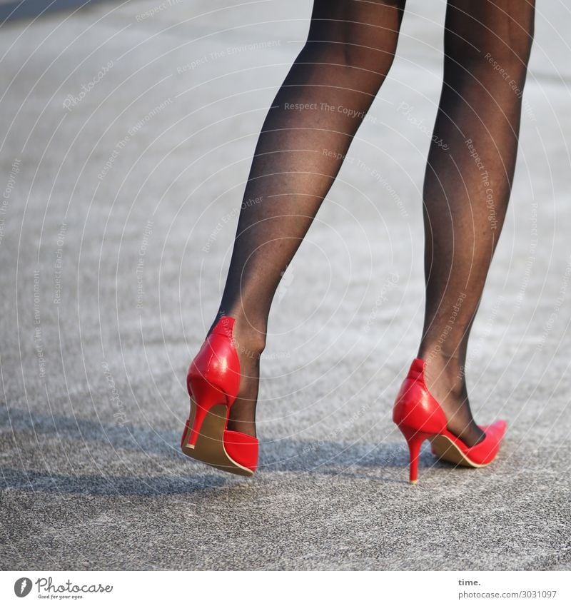 Beautiful woman legs wearing red heels over grey - Stock Image