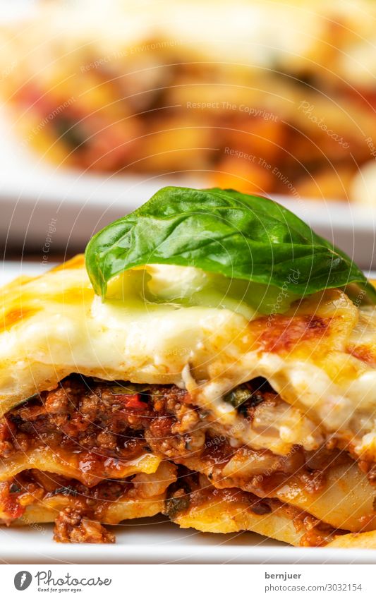 Close-up of the lasagna Meat Cheese Lunch Dinner Plate Wood Fresh Hot Kitsch Delicious Lasagne Eating Italian Meal pasta tribunal Basil homemade Kitchen