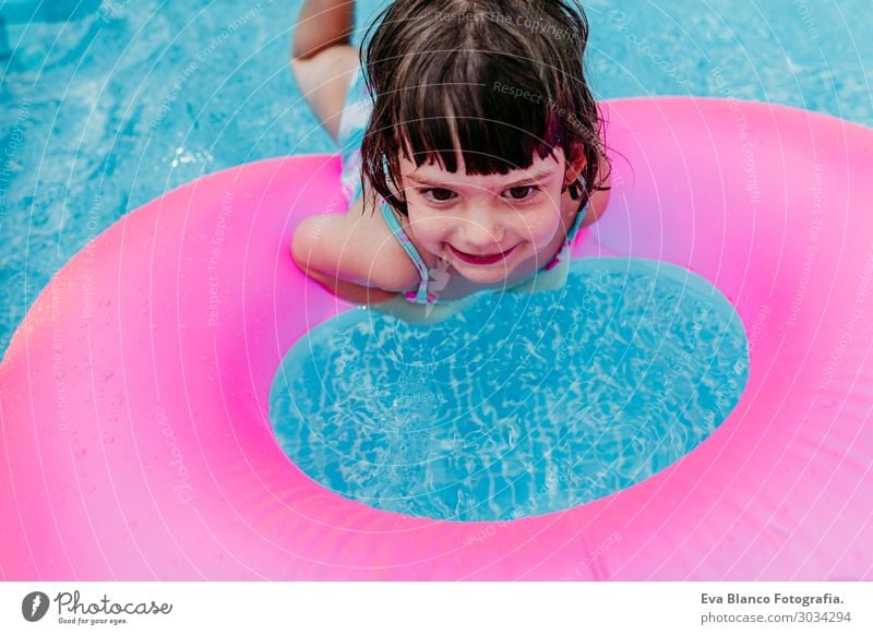 beautiful kid girl floating on pink donuts in a pool Lifestyle Joy Happy Beautiful Relaxation Swimming pool Leisure and hobbies Vacation & Travel Summer Sun