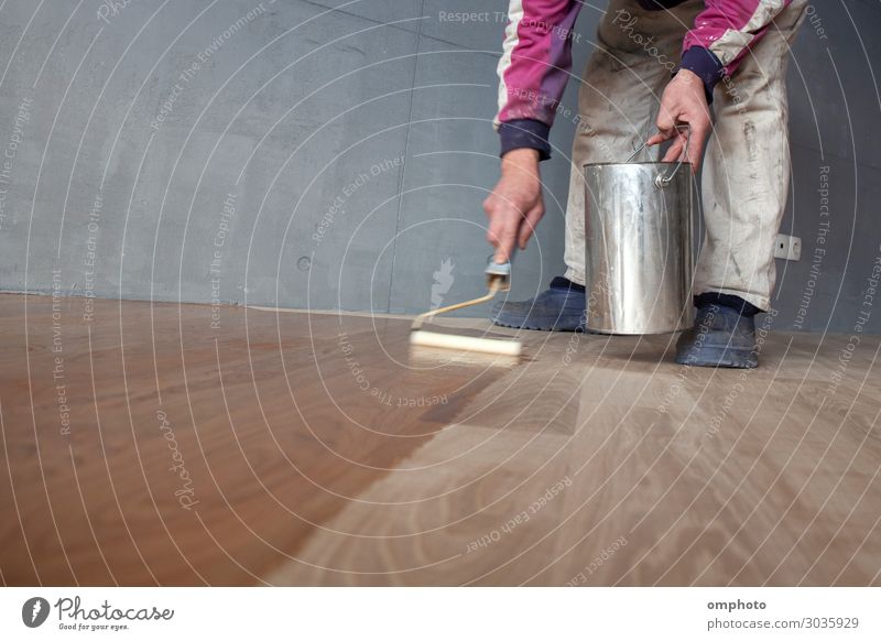 Worker varnishing lacquering an oak parquet floor by paint roller first layer after polishing House (Residential Structure) Work and employment Industry Tool