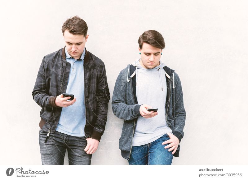 two male teenagers looking at their smartphone Lifestyle Leisure and hobbies mobile PDA Technology Entertainment electronics Internet Human being Masculine