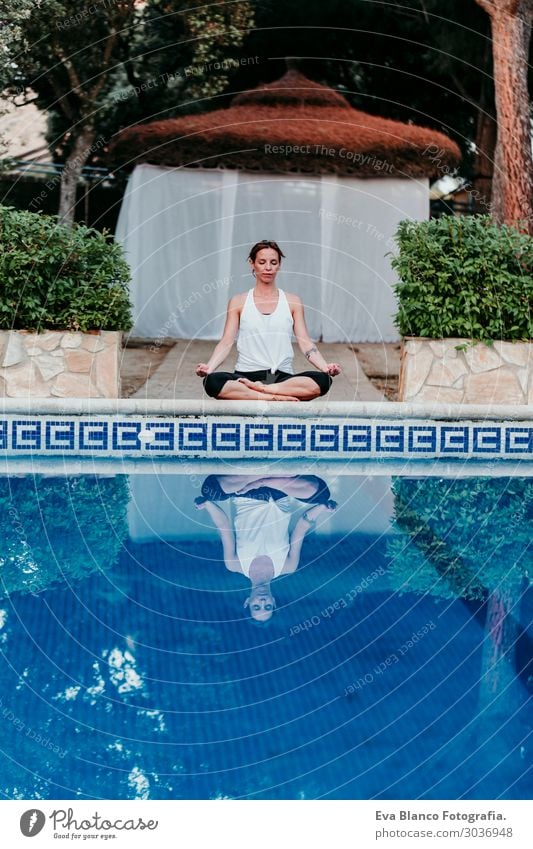 woman doing yoga by swimming pool. Yoga and mindfulness Lifestyle Beautiful Body Relaxation Calm Meditation Spa Swimming pool Leisure and hobbies