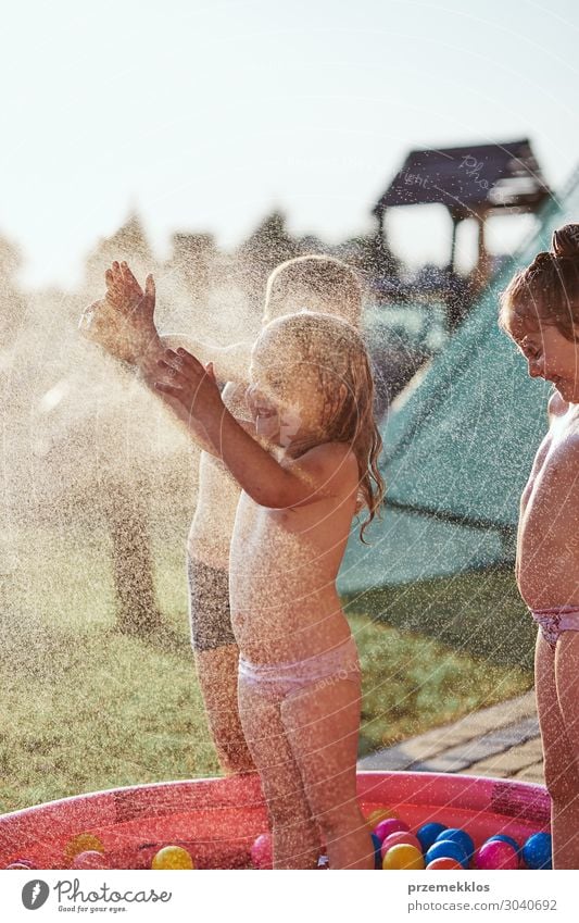 Little kids enjoying a cool water sprayed by their father Lifestyle Joy Happy Relaxation Swimming pool Vacation & Travel Summer Summer vacation Garden Child