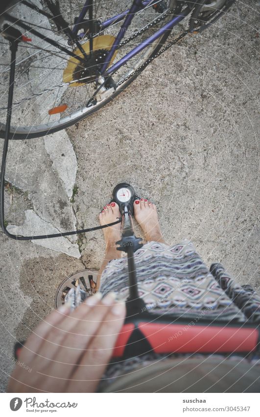 inflate bicycle Wheel Bicycle Spokes Hose pump Air Air pump Measure Hand Fingers Legs feet feminine Barefoot Pressure Display Air pressure Woman Bicycle chain