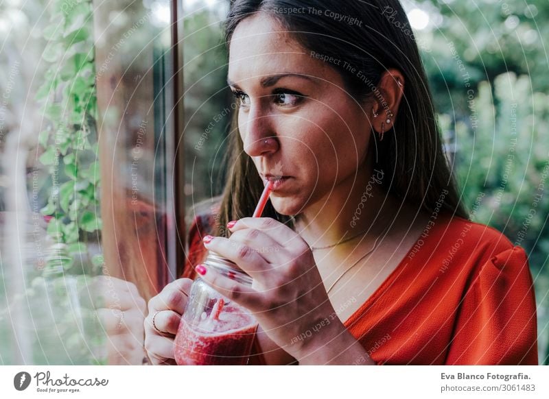 young beautiful woman standing by the window holding a healthy jug of smoothie. Home, indoors and lifestyle Vegetarian diet Drinking Natural Make-up Tasty