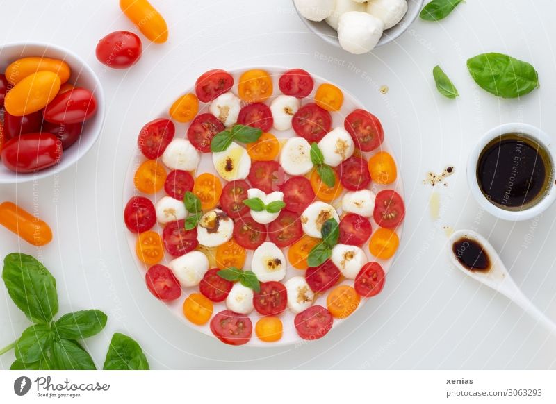 Tomato with mozzarella, basil and dressing with balsamic vinegar on white round plate with ingredients Lettuce Mozzarella Dressing Salad Herbs and spices Cheese