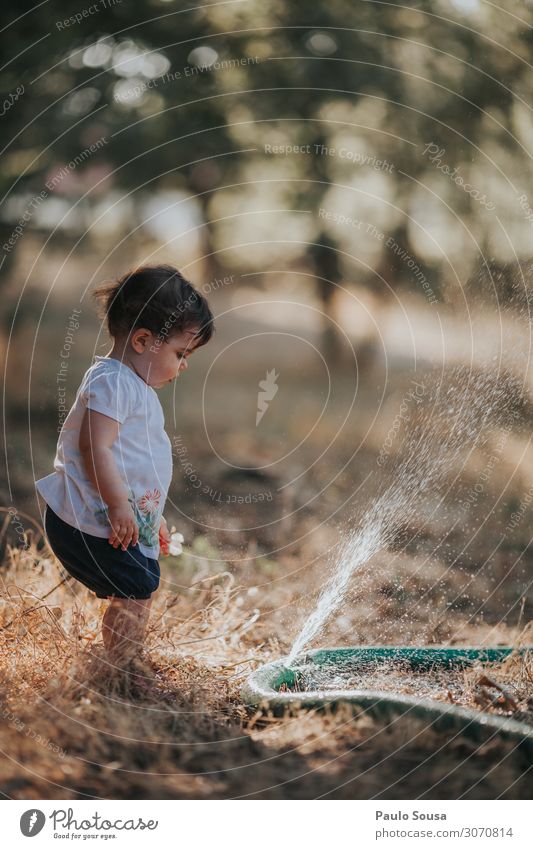 Baby Girl Standing By Water Spraying From Hose On Land Child childhood Summer Summer vacation Summer's day Exterior shot Colour photo Summery Infancy Nature