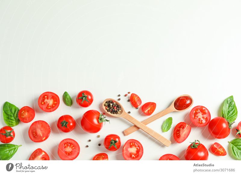 Flat lay composition with fresh tomatoes, pepper, basil and wooden spoons on white background, space for text. Ripe vegetables spice garlic sauce cooking red