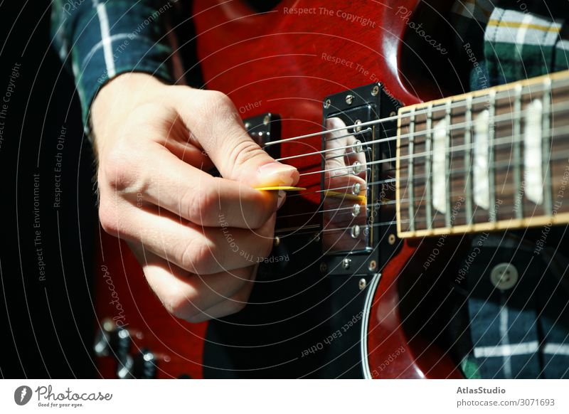 Man playing on electric guitar against dark background, closeup instrument flare live pick musician young table space blues song solo text player accessories