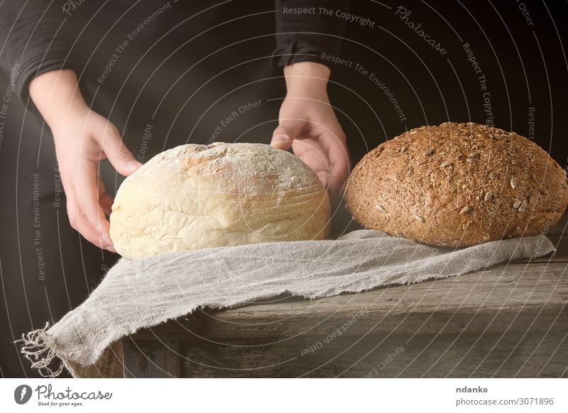 two female hands lay on a table baked white round bread Dough Baked goods Bread Breakfast Sun Table Kitchen Human being Woman Adults Arm Hand Wood Old Eating