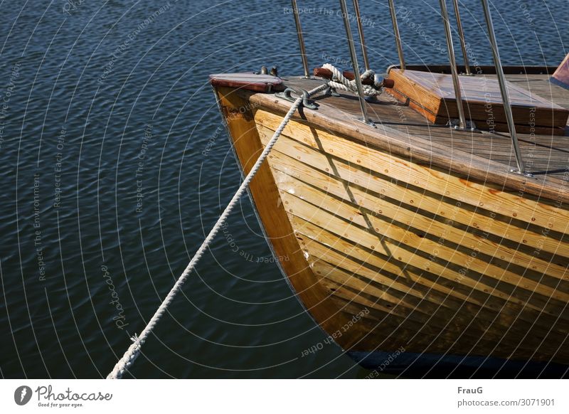 Wooden boat in the evening sun Water Ocean Waves Navigation Watercraft ship wooden boat leash Rope mooring rope moored Maritime Harbour Light Evening sun Shadow