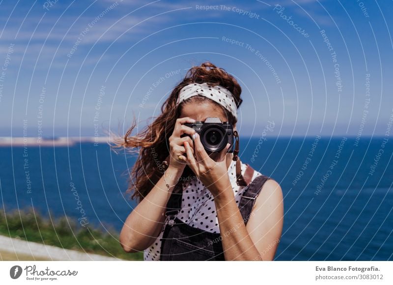 young caucasian tourist woman outdoors taking pictures with a reflex camera on a windy and sunny day. Lifestyle, travel and summertime Caucasian European Spring