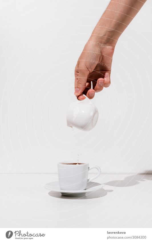 Woman's hand pouring almond milk into cup of coffee Beverage Breakfast Caffeine ceramic creamer Cup Fresh Hand Hot Milk Morning Mug Saucer Tea White