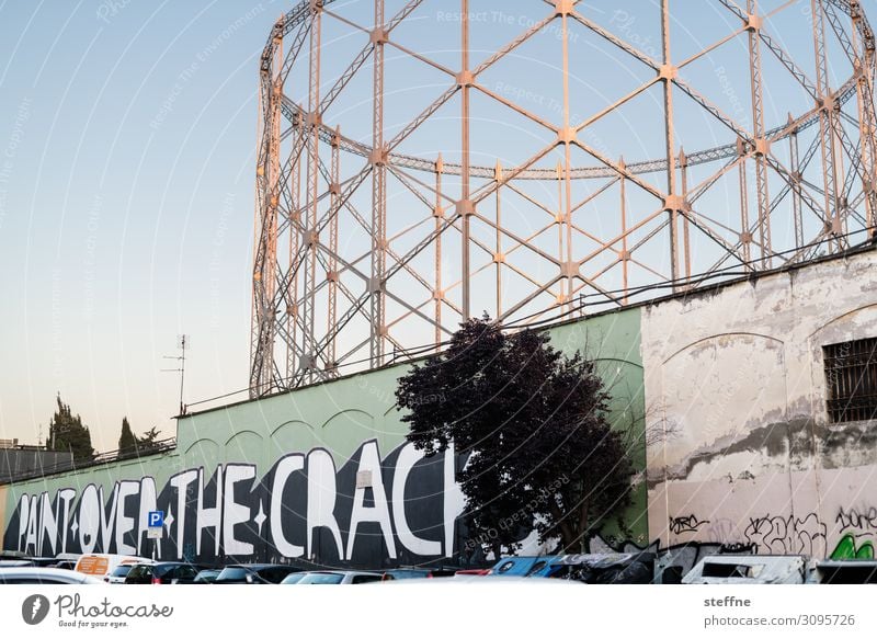 gasometer and mural graffiti Town Industrial plant Ruin Facade Graffiti Gasometer Rome Evening sun Society dilapidated Old Change motto Figure of speech
