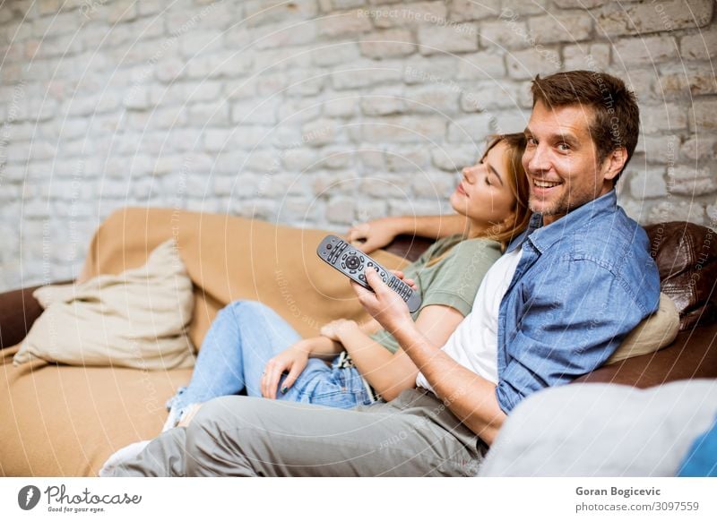Smiling young couple relaxing and watching TV at home Lifestyle Joy Relaxation Flat (apartment) Sofa Technology Human being Woman Adults Man Family & Relations
