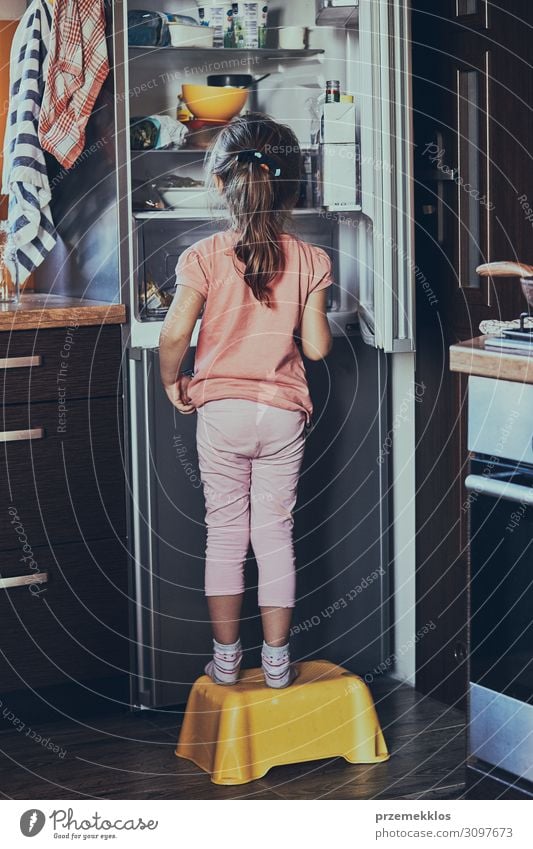 Little girl standing on a childs stool in front of opened fridge Lifestyle Kitchen Child Girl 1 Human being 3 - 8 years Infancy Stand Authentic Good Small