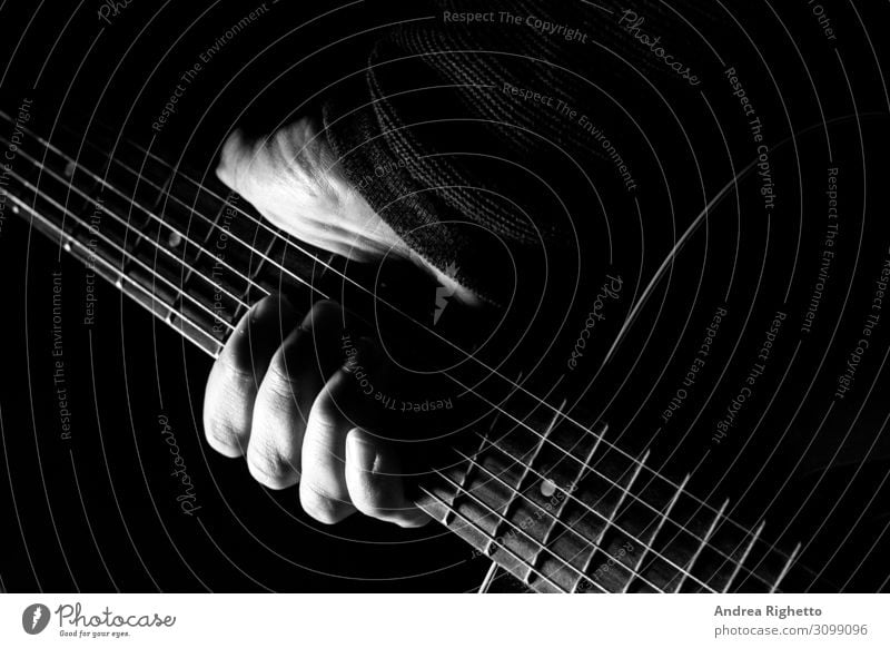 Hand holding an acoustic guitar with black background with a dramatic and  cinematic tone in chiaroscuro - a Royalty Free Stock Photo from Photocase