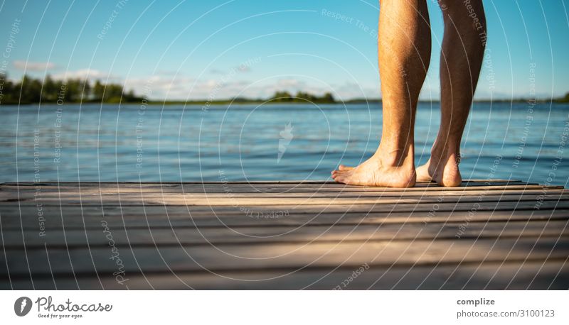 Man standing barefoot on a wooden jetty by the lake. Panorama. Healthy Wellness Harmonious Relaxation Calm Sauna Swimming & Bathing Vacation & Travel