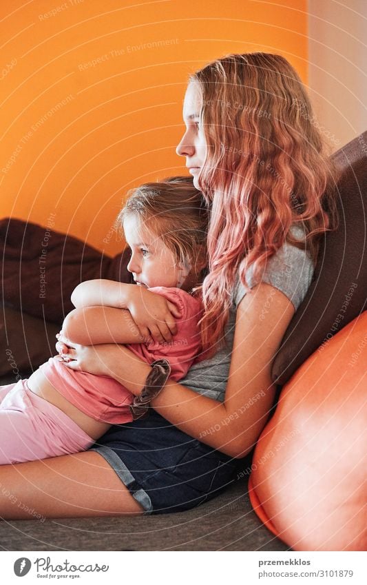 Teenage girl and her little sister watching TV Leisure and hobbies Child Girl Young woman Youth (Young adults) Woman Adults Sister Family & Relations Infancy 2