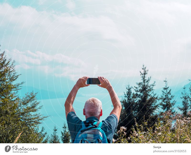 Man over 40 on a mountain with mobile phone and view of a lake Lifestyle Freedom Hiking Masculine Adults 1 Human being 45 - 60 years Nature Water Sky Sunlight