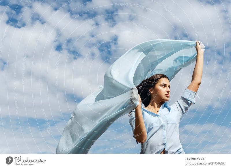 Young female holding cut of blue cloth up in the sky Air Horizon Height Exterior shot Attractive Summer Nature Happy Adults Loneliness Blue Cloth Clouds Cut
