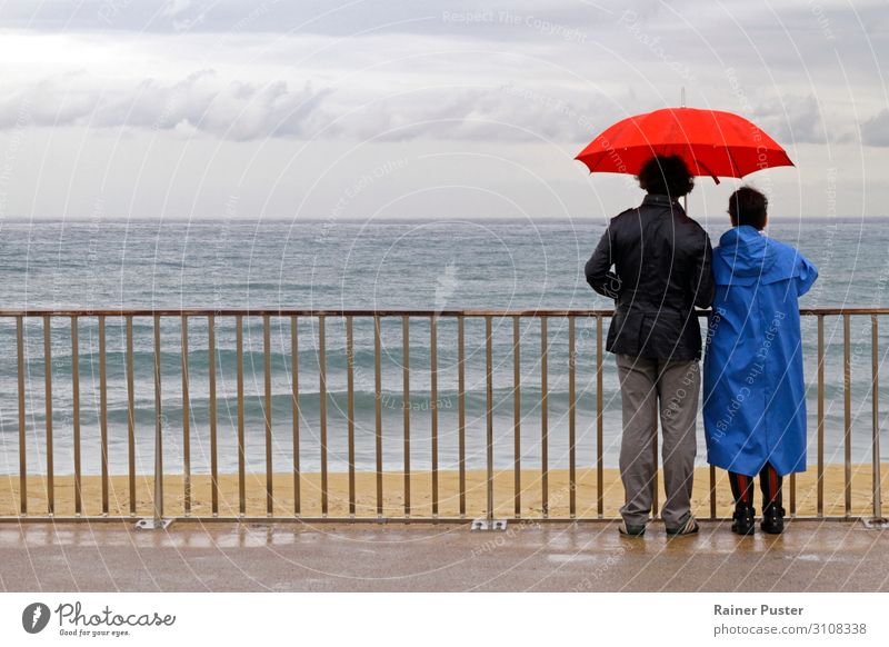 Couple with umbrella on the coast near Barcelona Human being 45 - 60 years Adults Clouds Autumn Bad weather Rain Beach Umbrellas & Shades Looking Wait Together
