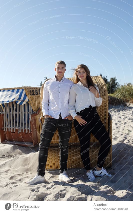 Young man and young woman on the beach in front of a beach chair Joy already Harmonious Summer Summer vacation Sun Beach Young woman Youth (Young adults)