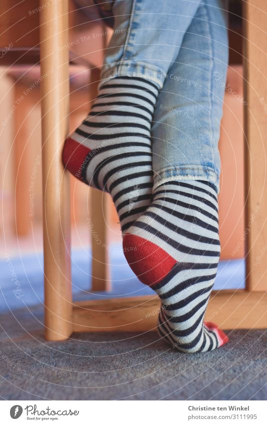 A girl with colorful striped stockings stands on the shadow of a