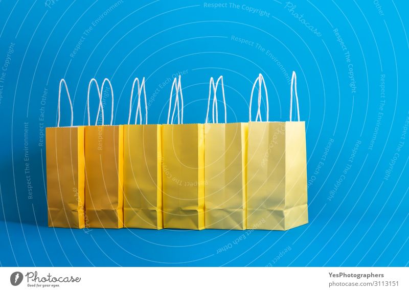 Yellow shopping bags on a blue background, Shopping concept Lifestyle Joy Happy Winter Feasts & Celebrations Christmas & Advent New Year's Eve Paper Package