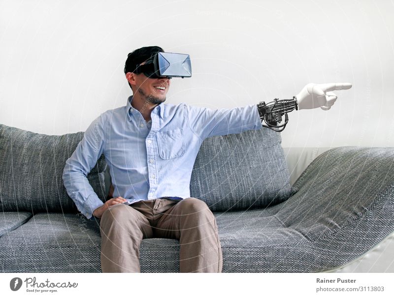Man on sofa with virtual reality glasses and virtual arm Economy Media industry Telecommunications To talk Headset Computer Hardware VR Glasses Masculine