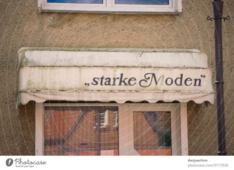 Starke Moden stands on an awning of a shop that is closed, on the street. Below you can see the entrance door. Design Trip House (Residential Structure) Summer