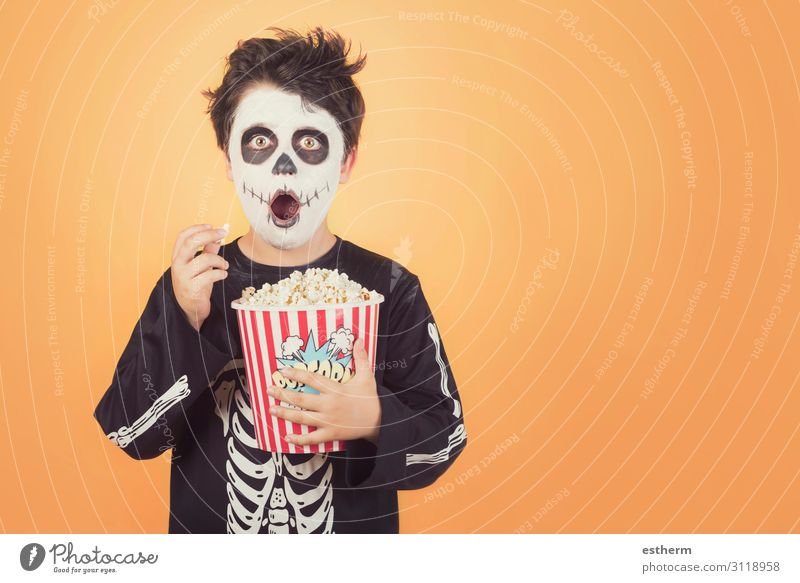Happy Halloween.Surprised child in a skeleton costume with popcorn against orange   background Food Eating Medical treatment Entertainment Feasts & Celebrations