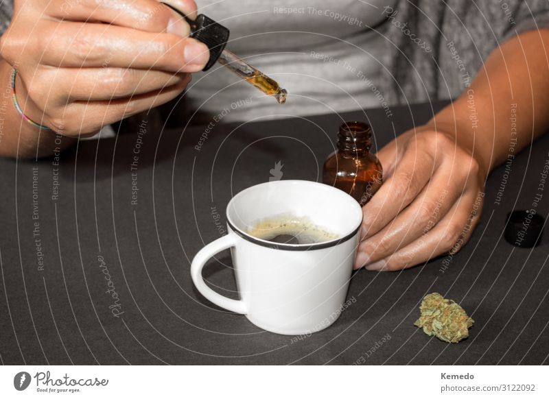 Woman pouring cannabis oil (made with marijuana) in a coffee cup Dessert Herbs and spices Breakfast Beverage Coffee Cup Mug Lifestyle Joy Healthy Health care