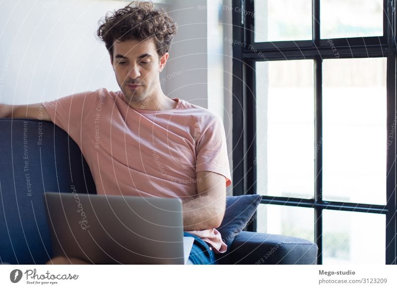 Young man relaxing on the sofa with a laptop Lifestyle Joy Happy Relaxation Calm Leisure and hobbies Reading Flat (apartment) House (Residential Structure) Sofa