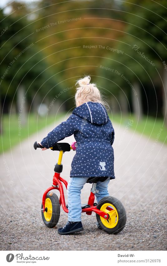 Child rides a bicycle Bicycle Kiddy bike Self-confident Bike helmet Safety Deep depth of field Lanes & trails off Driving Cycling Study