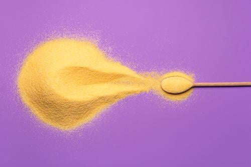 Corn flour pile and a spoon on purple background Grain Vegetarian diet Spoon Healthy Eating Fresh Natural Yellow Gold Violet above view agriculture alimentary