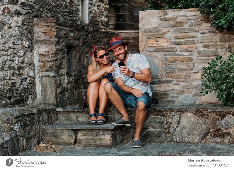 Young couple using smartphone on the steps of an old town Lifestyle Joy Vacation & Travel Tourism Summer vacation Cellphone Technology Telecommunications
