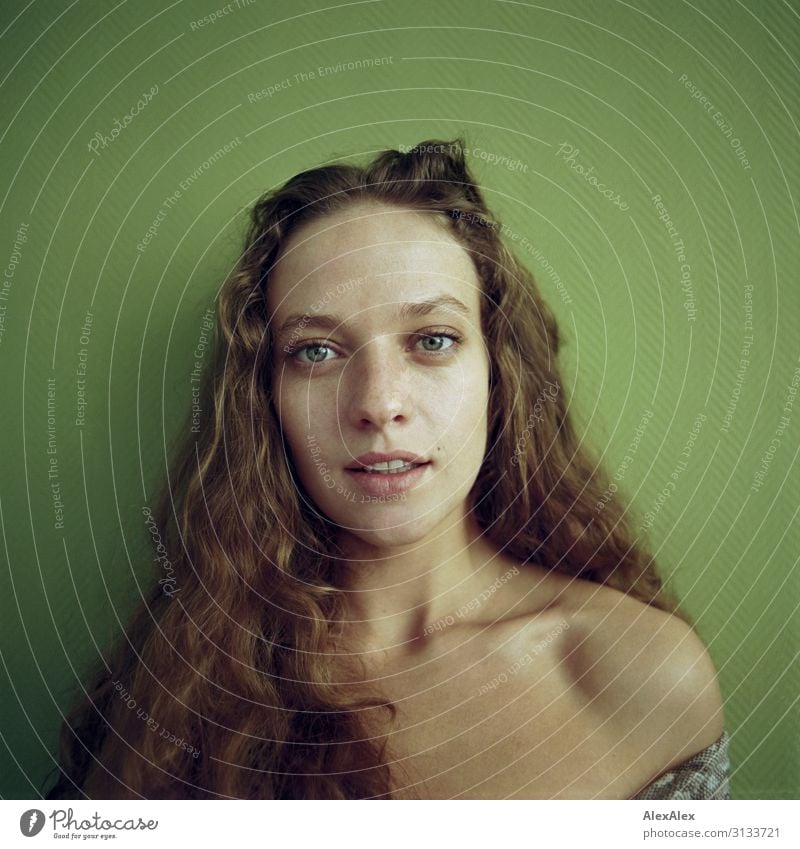 Young woman sitting on a chest of drawers in front of a yellow wall - a  Royalty Free Stock Photo from Photocase