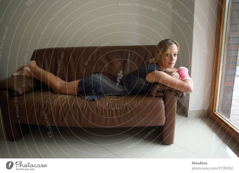Beautiful young athletic slim woman lying on a brown sofa Style pretty Life Well-being Living or residing Sofa Room Young woman Youth (Young adults) Legs