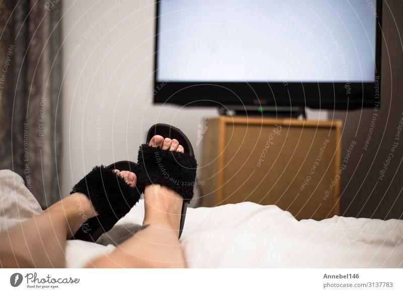 Person watches TV at night in bed with black Flip Flops. Beverage Joy Relaxation Leisure and hobbies Sofa Table Bedroom Entertainment Screen Technology