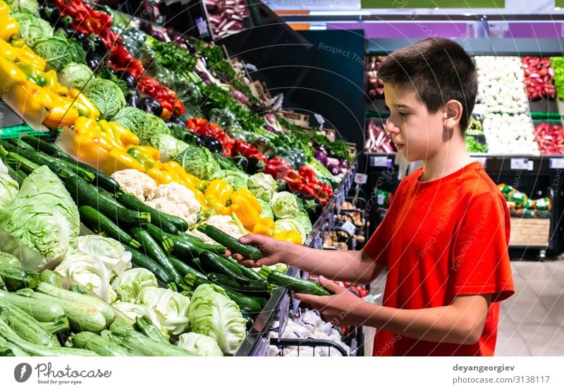 Child selecting vegetables on shelf in supermarket. Food Vegetable Vegetarian diet Shopping Marketplace Stand Fresh Natural shopper teenager kid healthy Variety