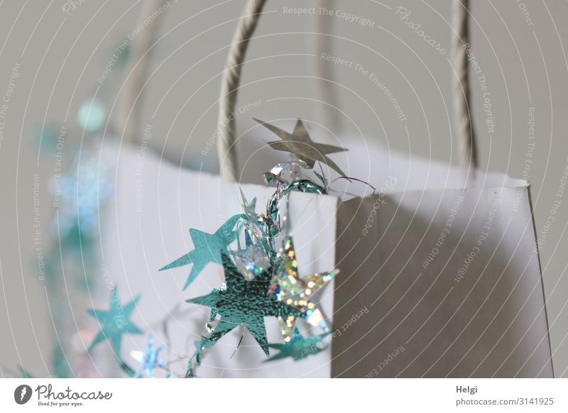 turquoise and silver stars hang as decoration on a white paper bag Feasts & Celebrations Christmas & Advent Paper Decoration Paper bag Star (Symbol) Gift Sign