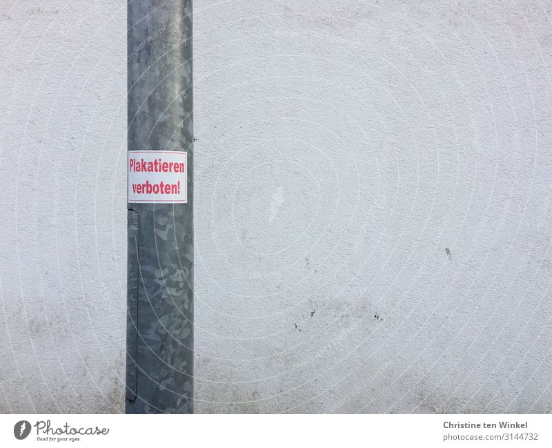 lamppost with sticker 'Placarding prohibited' in front of a dirty white wall Wall (barrier) Wall (building) Lamp post Concrete Metal Signs and labeling Signage