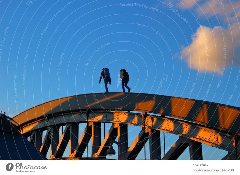 Pedestrians on bridge railings in the evening sun Technology Human being Friendship 2 18 - 30 years Youth (Young adults) Adults Bridge Architecture Street