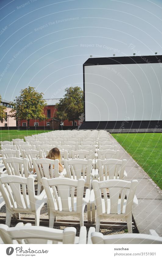 teenager sitting all alone in an open-air cinema in front of a big screen Introduction Cinema Canvas by oneself take a seat Sit all clear Too early out