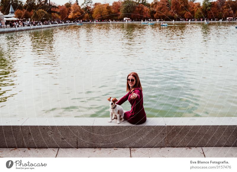 young woman and cute dog by the lake in an urban park. Love for animals concept. Retiro park Madrid Woman Dog Pet Lake Park Exterior shot City Embrace Together