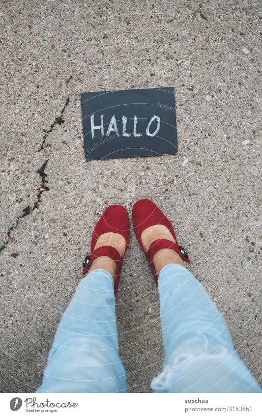 Woman stands in front of a small board with the word "hello" written on it . feminine Legs foot Footwear jeans Stand Street Asphalt Blackboard Written Chalk